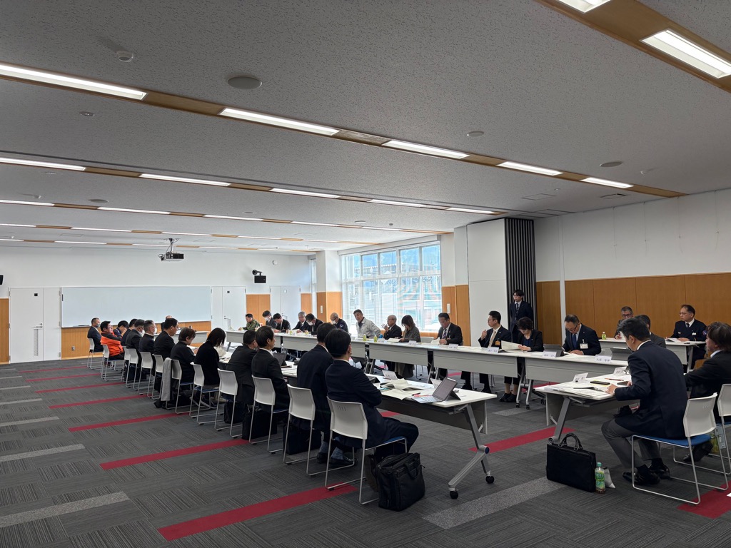 コの字型に設置されたテーブルと椅子に座り話を聞いている様子の写真の拡大画像