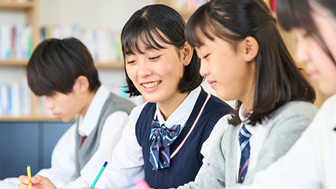 制服を着た女の子2人が何かを書き込みながら話をしている