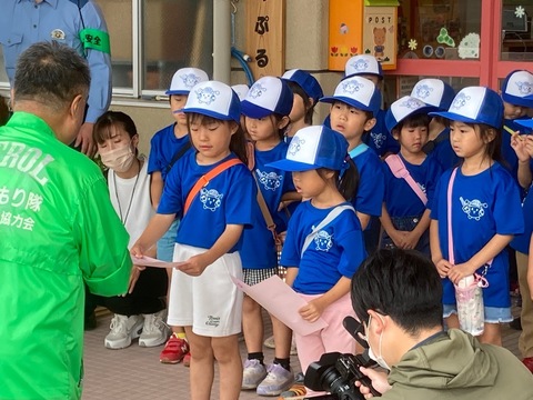 園児へ委嘱状を渡す係りの男性と真剣な眼差しでもらう子供たちを撮影している写真