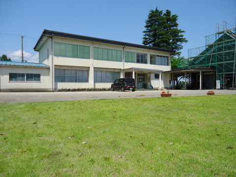 芝生で綺麗な緑が広がる南砺市大鋸屋交流センターの入り口側を外から撮影した写真
