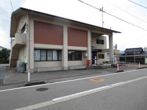 入口に赤いポストが置いてあり道路横に建つ南砺市福野西部交流センターを斜め前から撮影した写真