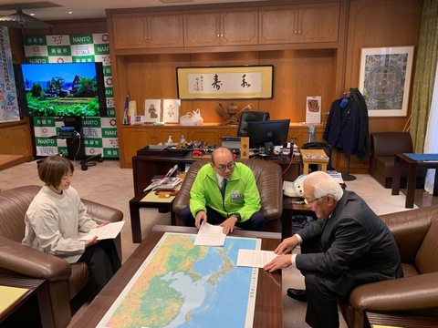 南砺市協働のまちづくり推進会議の男性が田中市長に提言の説明をしている様子を撮影した写真
