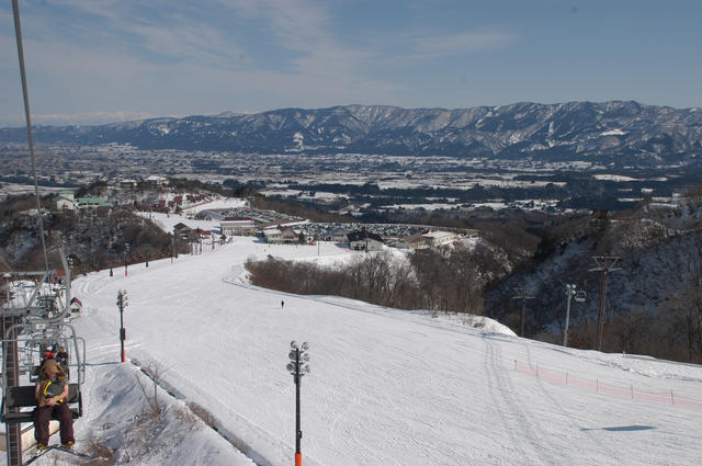 奥に山々が見えるゲレンデの左側にリフトがあるIOX-AROSAスキー場の写真