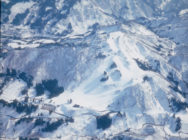 全体の山々に雪が積もっているたいらスキー場を空撮した写真