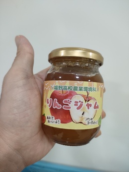 瓶に入ったリンゴジャムを手に持っている写真