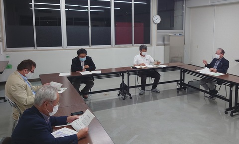 コの字型に並べられた長机の席に参加者達が座り、会議が行われている写真