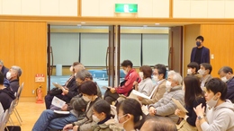 意見交換会に参加している沢山の参加者の中の1人の女性がマイクを持ち意見を出している様子の写真