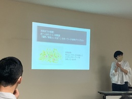 女性が立っている横の壁に映し出された資料をアップで写した写真