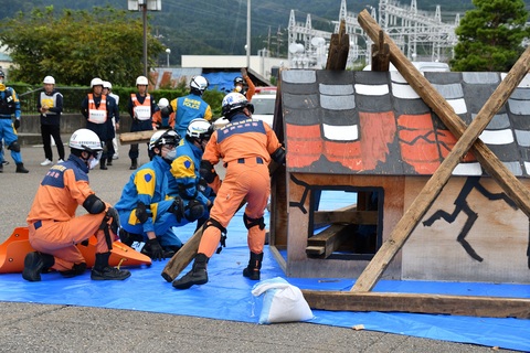 倒れた家屋を使い救出訓練をしている消防隊員の写真