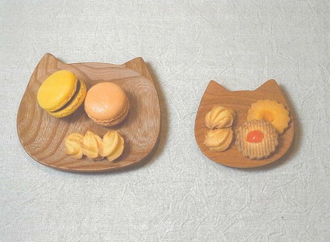 お菓子が盛り付けられている大きさの異なるネコの顔のかたちをした木製のニャンコ皿2枚の写真
