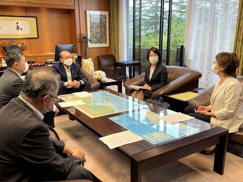 彼谷環委員長、楠井悦子副委員長、他男性2名と田中市長がテーブルを囲むようにソファーに座って話をしている写真
